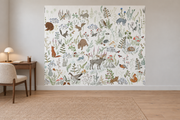Cerfs & fleurs, motif 3 : animaux des sous-bois, élan, ours, renards, lapins, oiseaux et plantes fines sur fond blanc cassé, posé en papier peint dans un bureau familial clair avec table de travail en bois.