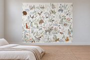 Cerfs & fleurs, motif 3 : animaux des sous-bois, élan, ours, renards, lapins, oiseaux et plantes fines sur fond blanc cassé, posé en papier peint dans une chambre d’enfant lumineuse avec lit bas et linge clair.