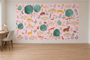 Cerfs & fleurs, motif 8 : cerfs jaunes, ours, renards, lapins et oiseaux parmi de grands arbres turquoise sur fond rose pâle, posé en papier peint dans un bureau familial clair avec table de travail en bois.