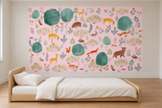 Cerfs & fleurs, motif 8 : cerfs jaunes, ours, renards, lapins et oiseaux parmi de grands arbres turquoise sur fond rose pâle, posé en papier peint dans une chambre d’enfant lumineuse avec lit bas et linge clair.