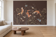Cerfs & fleurs, motif 10 : trois renards bondissants, oiseaux, lapins gris bleuté et fleurs fines sur fond brun natif, posé en papier peint dans un salon familial lumineux avec canapé en lin clair.