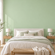 Papier peint vert sauge derrière le lit d’une chambre claire.