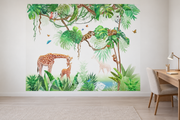 Safari aquarelle, motif 2 : jungle aquarellée verte sur fond blanc, girafe penchée vers son petit, petits animaux dans les branches et papillons, posé en papier peint dans un bureau familial clair avec table de travail en bois.