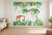 Safari aquarelle, motif 2 : jungle aquarellée verte sur fond blanc, girafe penchée vers son petit, petits animaux dans les branches et papillons, posé en papier peint dans une chambre d’enfant lumineuse avec lit bas et linge clair.