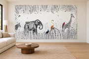 Safari aquarelle, motif 5 : jungle finement dessinée noir et blanc, éléphant à gauche, girafe à droite, zèbre coupé au bord gauche et oiseaux colorés, posé en papier peint dans un salon familial lumineux avec canapé en lin clair.