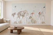 Safari aquarelle, motif 6 : jungle aquarellée très pâle sur fond gris sauge clair, éléphant et tortue, zèbre, flamant rose, petite chouette, girafe et oiseaux, posé en papier peint dans un salon familial lumineux avec canapé en lin clair.